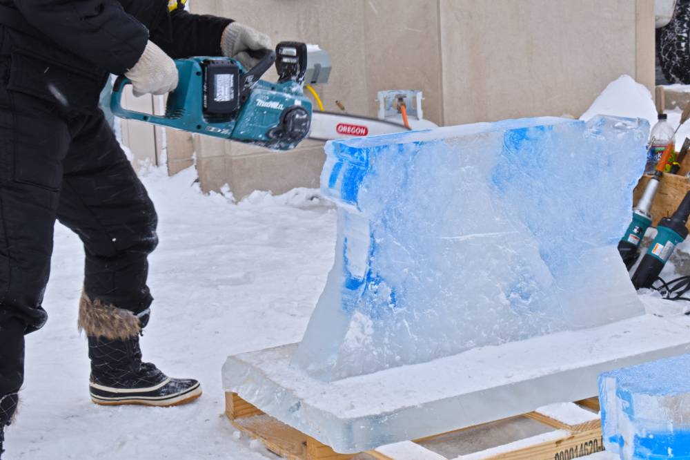 person with chainsaw against block of ice